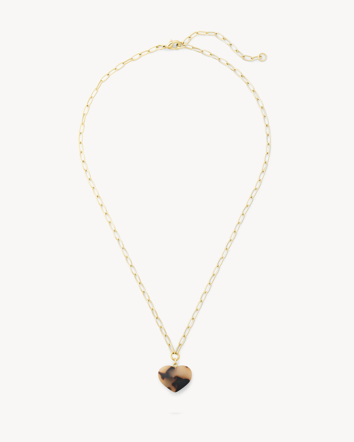 A delicate gold chain necklace with a small heart-shaped pendant featuring a tortoiseshell pattern, displayed on a clean off-white background.